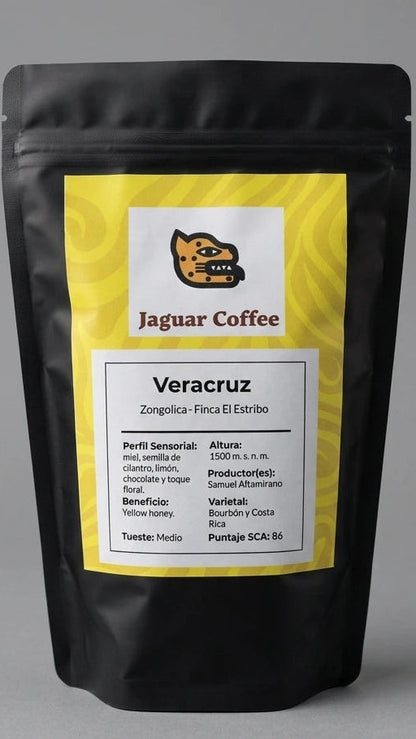 La iluminación de estudio, difusa y uniforme, resalta el diseño limpio de la etiqueta amarilla y blanca de Jaguar Coffee. En ella se leen claramente los detalles técnicos del lote de Samuel Altamirano: 1500 m.s.n.m., proceso Yellow Honey, varietales Bourbón y Costa Rica, y un puntaje SCA de 86, proyectando una imagen de elegancia salvaje y calidad experta.