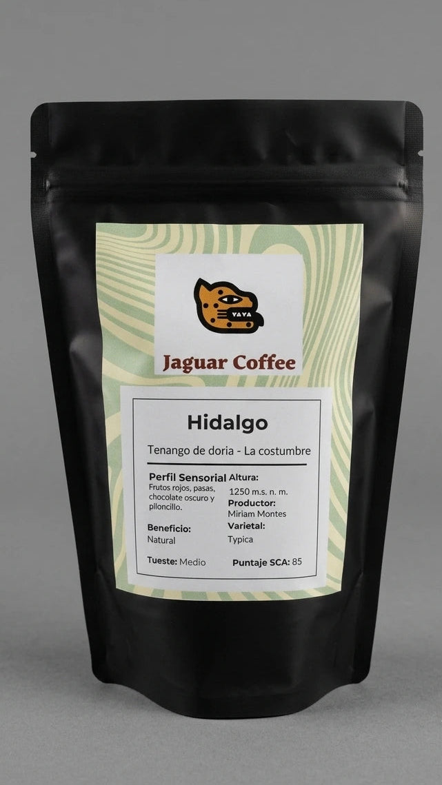 Bolsa negra mate de café de especialidad Jaguar Coffee, origen Tenango de Doria, Hidalgo, Finca La Costumbre. Etiqueta frontal con patrón de ondas verde olivo, proceso Natural, tueste medio y perfil sensorial con notas a frutos rojos, pasas, chocolate oscuro y piloncillo.