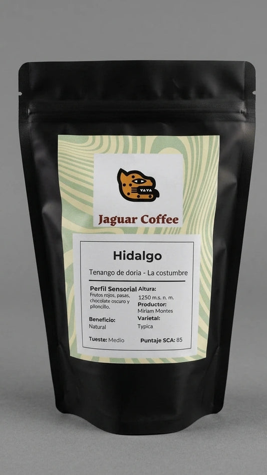 Bolsa negra mate de café de especialidad Jaguar Coffee, origen Tenango de Doria, Hidalgo, Finca La Costumbre. Etiqueta frontal con patrón de ondas verde olivo, proceso Natural, tueste medio y perfil sensorial con notas a frutos rojos, pasas, chocolate oscuro y piloncillo.